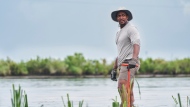 This image released by National Geographic shows actor/host Anthony Mackie wading in the Bayous near Violet, La., during the filming of "Shark Beach with Anthony Mackie." (Brian Roedel/National Geographic via AP)