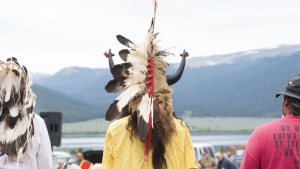 Ota Bluehorse wears a ceremonial headdress adorned with bison horns while attending a naming ceremony for a white buffalo calf, Wednesday, June 26, 2024, at the headquarters of the Buffalo Field Campaign in West Yellowstone, Mont. (AP Photo/Sam Wilson)