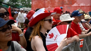 A person cools themselves with a fan during the Canada Day noon show in Ottawa on Saturday, July 1, 2023. THE CANADIAN PRESS/Justin Tang