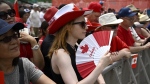 A person cools themselves with a fan during the Canada Day noon show in Ottawa on Saturday, July 1, 2023. (Justin Ting/The Canadian Press)