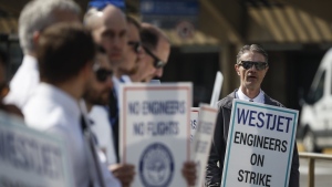 WestJet airplane mechanics stand in a the picket line at Calgary International Airport in Calgary, Saturday, June 29, 2024.THE CANADIAN PRESS/Jeff McIntosh
