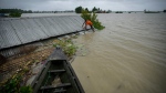A flood victim tries to fix a tin roof of his submerged house in Sildubi village in Morigaon district in the northeastern state of Assam, India, Tuesday, July 2, 2024. (AP photo/Anupam Nath)
