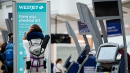 Passengers are seen in the WestJet check-in area at Pearson International Airport, in Toronto, Saturday, June 29, 2024. THE CANADIAN PRESS/Christopher Katsarov”