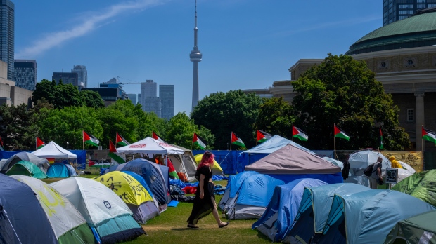 FILE - A woman walks between the tents in the pro-Palestinian encampment set up at the University of Toronto campus, in Toronto, Sunday, May 26, 2024. THE CANADIAN PRESS/Frank Gunn