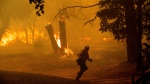 A firefighter runs while battling the Thompson Fire burning in Oroville, Calif., Tuesday, July 2, 2024. (AP Photo/Noah Berger)