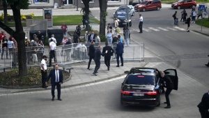 Bodyguards take Slovak Prime Minister Robert Fico in a car from the scene after he was shot and injured following the cabinet's away-from-home session in the town of Handlova, Slovakia, on May 15, 2024.  (Radovan Stoklasa/TASR via AP)