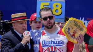 Patrick Bertoletti, right, reacts after winning the men's division in Nathan's Famous Fourth of July hot dog eating contest, Thursday, July 4, 2024, at Coney Island in the Brooklyn borough of New York. Bertoletti ate 58 hot dogs. (AP Photo/Julia Nikhinson)