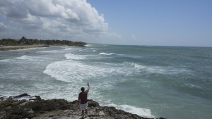 A man takes a video tfrom the rocky shore of Mirador beach ahead of Hurricane Beryl's expected arrival, in Tulum, Mexico, Thursday, July 4, 2024. (AP Photo/Fernando Llano)