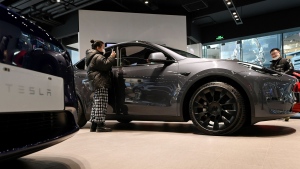 People look at a Tesla Model Y car at a Tesla showroom in Beijing, China in January 2021. (Wang Zhao / AFP / Getty Images via CNN Newsource)