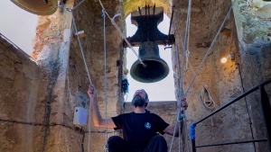 Sitting in a chair with ropes looped around both feet and hands, Joan Carles Osuna, a student of the Vall d'en Bas School of Bell Ringers, performs playing all four bronze bells at the church bell tower of the12th-century Sant Romà church, at the village of Joanetes, about two hours north of Barcelona, Spain, Saturday, July 29, 2024. (AP Photo/Emilio Morenatti)