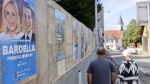 A couple walks past electoral posters showing far-right leaders Marine Le Pen and Jordan Bardella during second round of the legislative elections, Sunday, July 7, 2024 in Mittelschaeffolsheim , eastern France.  (AP Photo/Jean-Francois Badias)
