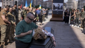 Partner of British combat medic, volunteer, Peter Fouche, 49 who was killed on June 27 during his work in East Ukraine, mourns during the funeral ceremony on the city's main square in Kyiv, Ukraine, Saturday, July 6, 2024.  (AP Photo/Alex Babenko)