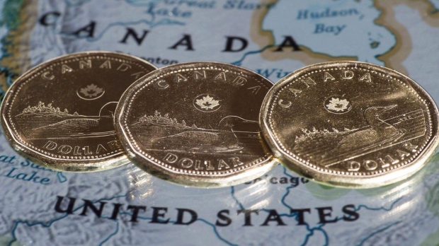 Canadian dollar coins are displayed on a map along the border of Canada and the United States of America, in Montreal in a January 9, 2014 file photo. THE CANADIAN PRESS/Paul Chiasson