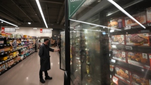 An employee overlooks foods near the frozen food section inside a Metro grocery store in Milton, Ont., on Friday, January 12, 2024. THE CANADIAN PRESS/Nathan Denette