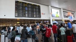 Travellers wait for information in front of a departure board at Brussels International Airport in Brussels, Friday, July 19, 2024. (AP Photo/Harry Nakos)