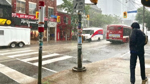 A man walks in the rain on Queen Street West in Toronto on Wednesday, July 24, 2024. (Bryann Aguilar/CP24)