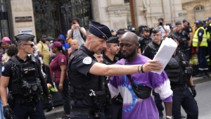 Police officers escort away man during a migrants' protest at the 2024 Summer Olympics, Thursday, July 25, 2024, in Paris, France. (AP Photo/David Goldman)