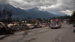 A fire truck travels past a devastated residential block in Jasper, Alta., on Friday July 26, 2024. Wildfires encroaching into the townsite of Jasper forced an evacuation of the national park and have destroyed over 300 of the town's approximately 1100 structures, mainly impacting residential areas. THE CANADIAN PRESS/Amber Bracken