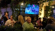People watch the television broadcast of the opening ceremony of the 2024 Summer Olympics in Paris, France via Kazakhstan satellite channel sitting in the Waterloo pub & bar in St. Petersburg, Russia, Friday, July 26, 2024. (AP Photo/Dmitri Lovetsky)