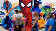 Convention attendees blur past a wall of illustrated Marvel superhero characters during preview night for Comic-Con International, Wednesday, July 24, 2024, in San Diego. (AP Photo/Chris Pizzello)
