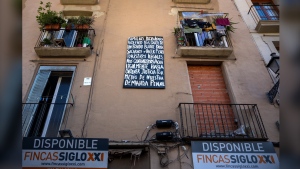 A block of flats, which is under threat of eviction, is photographed in downtown Barcelona, Spain, Wednesday, July 10, 2024. Barcelona City Hall announced last month that it would not renew any tourist apartment licenses after they expire in 2028. The banner reads in Spanish: Families who are under violent harassment by a vulture fund to evict us and make illegal tourist flats, we will stay here until we get justice through our criminal lawsuit. (AP Photo/Emilio Morenatti)