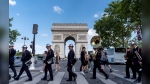 Members of a firefighter brigade band cross the street to perform at a ceremony at the Arc de Triomphe ahead of the 2024 Summer Olympics, Saturday, July 20, 2024, in Paris. (AP Photo/David Goldman)