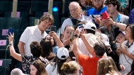Actor Tom Cruise, left in white, poses for pictures with fans as he attends the women's artistic gymnastics qualification round at the 2024 Summer Olympics, Sunday, July 28, 2024, in Paris, France. (AP Photo/Abbie Parr)