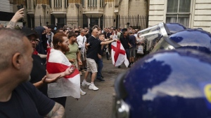 Protesters scuffle with police during the 'Enough is Enough' protest in Whitehall, London, Wednesday July 31, 2024, following the fatal stabbing of three children at a Taylor Swift-themed summer holiday dance and yoga class on Monday in Southport. (Jordan Pettitt/PA via AP)