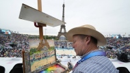 Peter Spens, of London, England, paints the scene at Eiffel Tower Stadium during a beach volleyball match at the 2024 Summer Olympics, Saturday, July 27, 2024, in Paris, France. (AP Photo/Robert F. Bukaty)