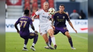 Toronto FC forward Federico Bernardeschi (centre) manoeuvres the ball around Orlando City SC forward  (77) and defender Kyle Smith (24) during the first half of their MLS soccer match in Toronto, Wednesday, July 3, 2024. THE CANADIAN PRESS/Cole Burston
