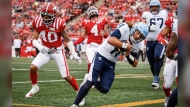 Toronto Argonauts quarterback Cameron Dukes (11) runs in a touchdown as Calgary Stampeders' Bentlee Sanders (40) and Cameron Judge (4) look on during first half CFL football action in Calgary, Alta., Sunday, Aug. 4, 2024. THE CANADIAN PRESS/Jeff McIntosh