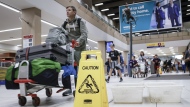 Travellers manoeuvre around buckets catching leaks as repairs are underway at the Calgary International Airport after parts of its domestic terminal building were closed late Monday due to damage caused by hail and heavy rainfall, in Calgary, Tuesday, Aug. 6, 2024. THE CANADIAN PRESS/Jeff McIntosh