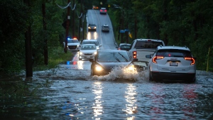 Cars drive slowly through flooded streets in Sainte-Anne-de-Bellevue on the Island of Montreal after heavy rains hit the area on Friday, August 9, 2024. THE CANADIAN PRESS/Peter McCabe 