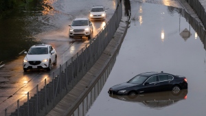 Cars drive slowly through water overflowing on to highway 40 in Sainte-Anne-de-Bellevue on the island of Montreal after heavy rains hit the area on Friday, August 9, 2024. THE CANADIAN PRESS/Peter McCabe 