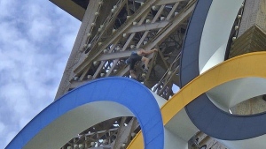 Shirtless man climbing Eiffel Tower 