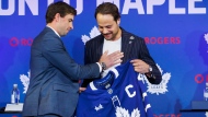 Toronto Maple Leafs’ Auston Matthews is handed his captain's jersey from former captain John Tavares during an announcement for Matthews' captaincy in Toronto, Wednesday, Aug. 14, 2024. THE CANADIAN PRESS/Cole Burston
