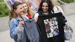 Francesca Abela, right, and Kylie Micallef both from Malta show off their Taylor Swift merchandise they have just purchased at Wembley Stadium in London, Wednesday, Aug. 14, 2024, ahead of attending Swift's concert at Wembley on Thursday. (AP Photo/Alastair Grant)