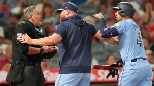 Home plate umpire Manny Gonzalez, left, argues with Toronto Blue Jays manager John Schneider, center, after throwing out George Springer during the seventh inning of a baseball game against the Los Angeles Angels, Tuesday, Aug. 13, 2024, in Anaheim, Calif. (AP Photo/Ryan Sun)