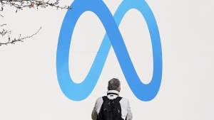 A person stands in front of a Meta sign outside of the company's headquarters in Menlo Park, Calif., March 7, 2023. (AP Photo/Jeff Chiu, File)