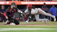 Cincinnati Reds Elly De La Cruz scores as he crosses the plate in front of Toronto Blue Jays catcher Brian Serven during fifth inning Interleague MLB baseball action in Toronto on Wednesday Aug. 21, 2024. THE CANADIAN PRESS/Chris Young