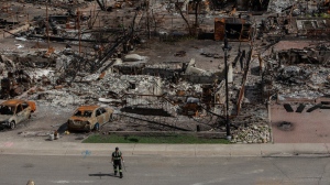 A worker walks in a devastated neighbourhood in west Jasper, Alberta on Monday August 19, 2024. A new study says planet-warming emissions from Canada's record-breaking wildfire season were quadruple the country's annual fossil emissions and on par with some of the largest global emitters. THE CANADIAN PRESS/Amber Bracken