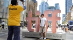 Volunteer Luke Bandara, left, takes a picture of Santiago Reyes, of Colombia, in front of the Toronto International Film Festival welcome sign on the opening day of the festival, Thursday, Sept. 5, 2024, in Toronto. (AP Photo/Chris Pizzello)