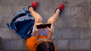 A 11-year-old boy plays with his father's phone outside school in Barcelona, Spain, Monday, June 17, 2024. (AP Photo/Emilio Morenatti, File)
