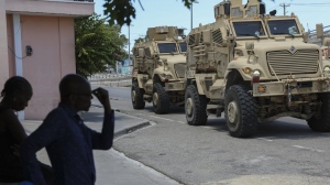 Kenyan police officers, part of a UN-backed multinational force, drive past residents in armored vehicles on the streets of Port-au-Prince, Haiti, Wednesday, Sept. 4, 2024. (AP Photo/Odelyn Joseph)