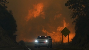 The Line Fire jumps highway 330 as an emergency vehicle is driven past Saturday, Sept. 7, 2024, near Running Springs, Calif. (AP Photo/Eric Thayer)