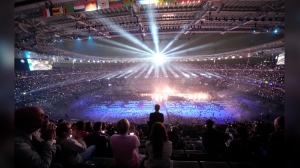 Spectators attend the closing ceremony of the 2024 Paralympics under the rain, Sunday, Sept. 8, 2024, in Paris, France. (AP Photo/Christophe Ena)