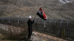 A Druze youth waves a Syrian flag during a rally calling for the return to Syria of the Golan Heights, captured by Israel in 1967, in Majdal Shams in the Israeli controlled Golan Heights, on the border with Syria, Feb. 14, 2022. (AP Photo/Ariel Schalit)