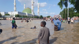 People walk through floodwaters following a dam collapse in Maiduguri, Nigeria, Tuesday Sept 10, 2024. (AP Photos/Joshua Olatunji) 