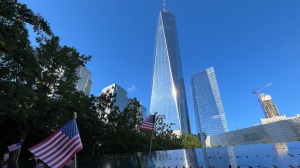 Flags are placed by the names of those killed during the Sept. 11, 2001, attacks at the reflecting pools at the National September 11 Memorial & Museum, Tuesday, Sept. 10, 2024, in New York. One World Trade Center rises in the background. (AP Photo/Donald King)