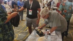 Fans gathered at the Royal Palm South Beach in Miami Beach, Fla., on Friday, Sept. 13, 2024, to celebrate the 40th anniversary of the television series "Miami Vice." Actor Bruce McGill, who guest-starred as retired detective Hank Weldon in the show's second season, signs a model Ferrari for a fan. (AP Photo/David Fischer)